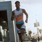 Person running outdoors wearing a colorful athletic outfit with palm trees and buildings in the background (White)