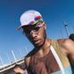 Man wearing a colorful cap and sunglasses with a clear blue sky in the background (White)