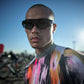 Man wearing a colorful outfit and sunglasses with bicycles in the background (Black)