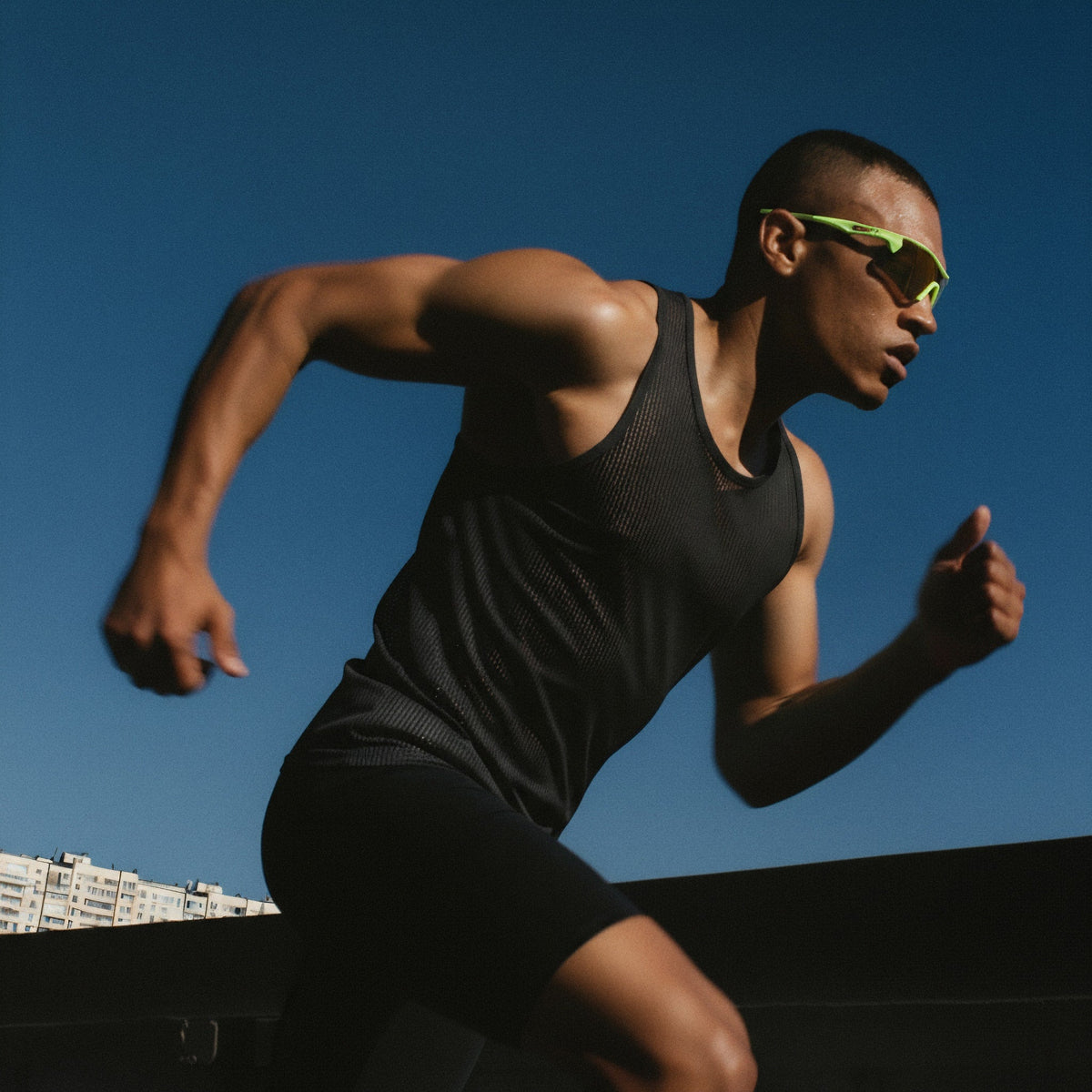 Athlete running outdoors with a clear blue sky (Green)
